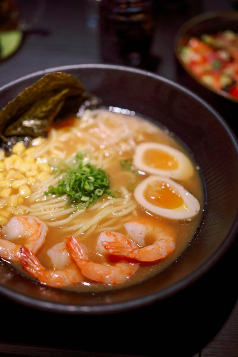 A savory bowl of shrimp ramen with corn, eggs, and seaweed, perfect for comfort food lovers.